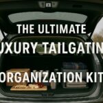 "Open SUV tailgate showing organized tailgating setup with storage containers, cutting board with food, and blankets in parking lot - Ultimate Luxury Tailgating Organization Kit"